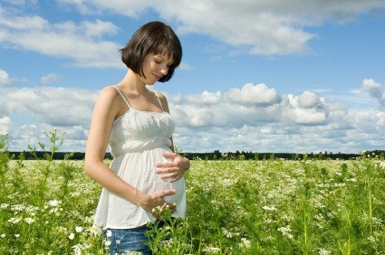 Pregnant woman smiling on a field