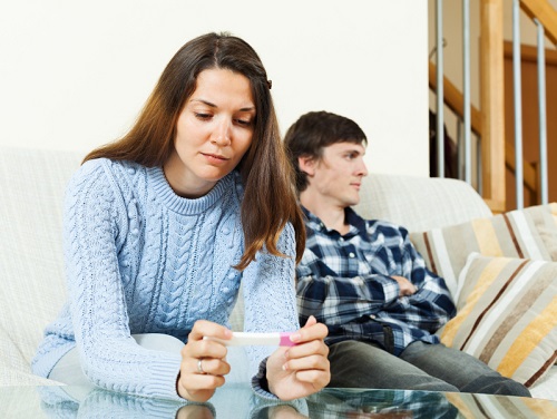 worried woman with pregnancy test against  man