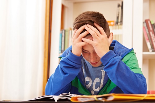 Male teenager worried doing homework