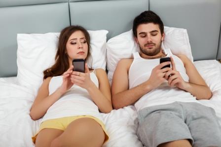 Happy Couple in a Bed with Mobile Phones
