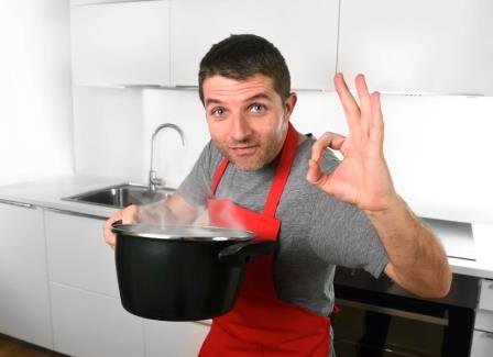 happy young man satisfied with taste of his cooking giving ok sign