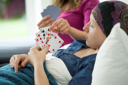 Cancer girl playing cards in hospital bed