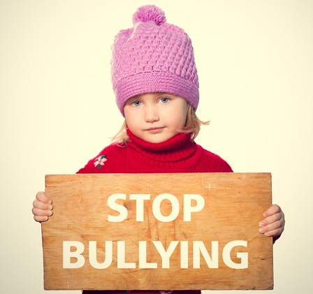 Little girl holding Board with text STOP BULLYING.