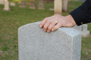 coping with grief and loss - man beside headstone