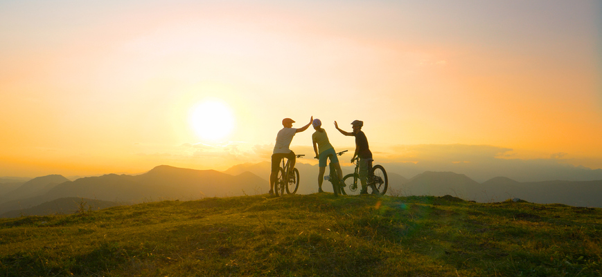 SUN FLARE: Mountain biking friends high five after reaching summit at sunrise